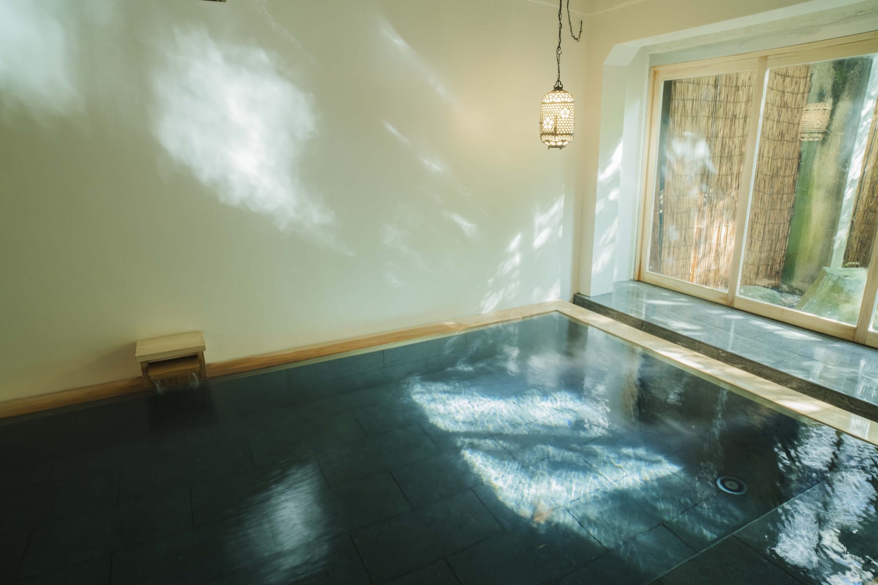 A stone hot spring bath with light moving on the water